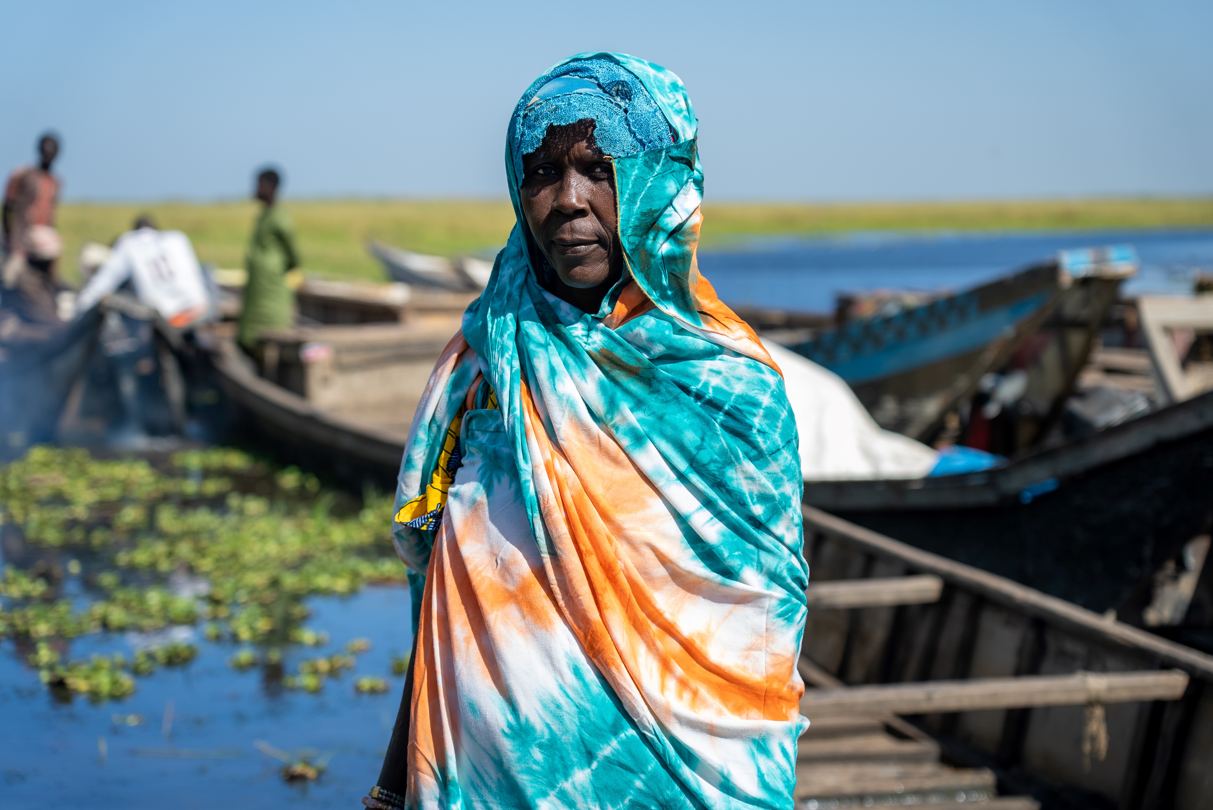 a person in a blue dress standing next to a body of water