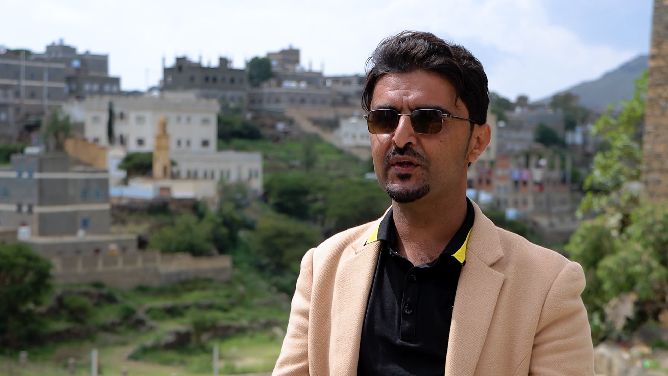 a man wearing sunglasses and standing in front of a building