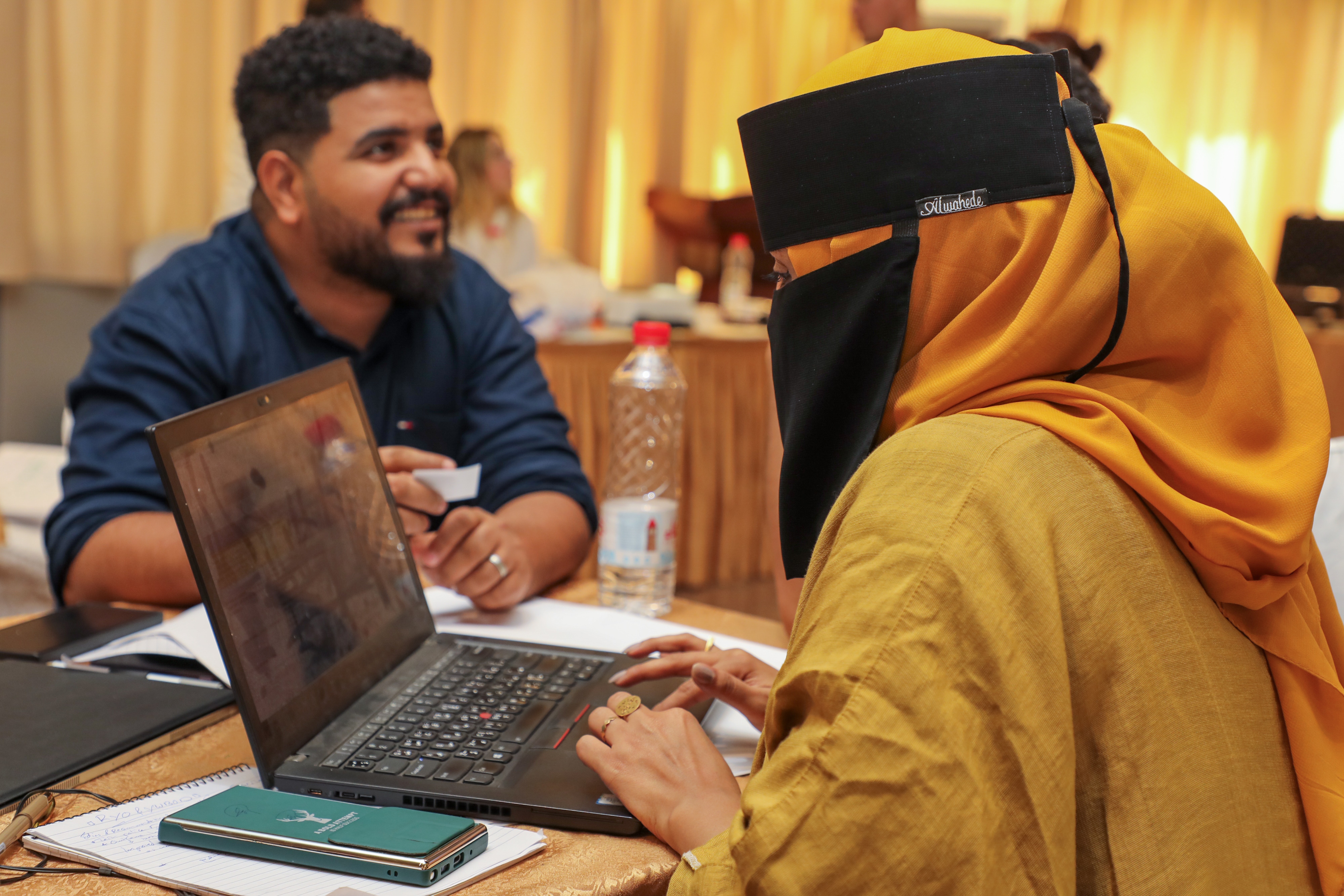 a person sitting at a table using a laptop computer